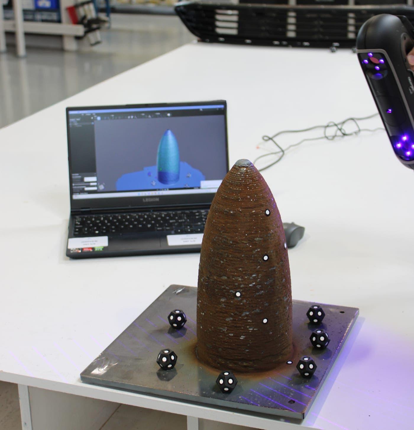 Håndholdt 3D-laserscanning af et metalprintet emne, med scanningen på skærmen